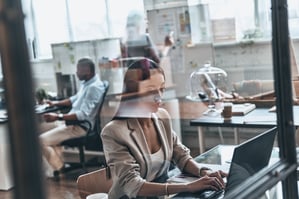 full-concentration-top-view-modern-young-woman-using-computer-while-working-glass-wall-office