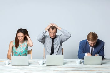 Tres trabajadores desesperados frente a sus equipos informáticos